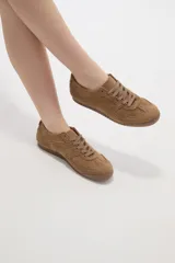 Zapatillas de estilo urbano color chocolate, confeccionadas en material textil tipo gamuza, con cordones al tono y suela de goma plana.