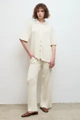 Pantalón de punto acanalado en color crema, con corte recto y tiro alto, confeccionado en algodón.