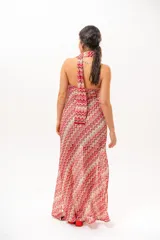 Vestido largo de crochet con escote strapless y lazo integrado para el cuello, con diseño de patrón en zigzag en tonos rojos, blancos y beige, y aberturas laterales en la falda.