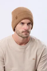 Gorro tejido de punto acanalado en color azul marino, con vuelta y etiqueta decorativa de cuero sintético en el lateral.