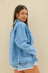 Campera de denim azul de corte oversize, con bolsillos frontales aplicados y cierre con botones metálicos.