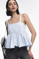 Top de tirantes con escote recto y diseño peplum con dos volados horizontales. Confeccionado en tejido de algodón con textura de microcuadros.