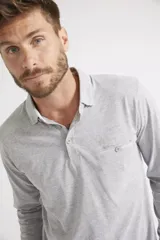 Remera polo de manga larga para hombre, confeccionada en algodón. Presenta un diseño de ajuste regular, con cuello clásico, cierre frontal con botones, bolsillo delantero con botón y logo bordado.