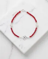 Pulsera de cuentas de cristal rojo con dije central de trébol de cuatro hojas en plata 925 y dos perlas pequeñas. Cuenta con cadena de alargue para ajuste.