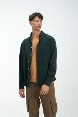 Camisa de manga larga verde oscuro confeccionada en pana fina de algodón. Tiene un bolsillo en el pecho, botones blancos y calce clásico.