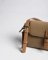 Bandolera XL de símil cuero con textura granulada, solapa frontal con tira y hebilla, y correa ajustable y desmontable en tono suela. Cuenta con herrajes dorados envejecidos y el logo de la marca en relieve.