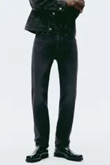 Jean de cinco bolsillos en denim de algodón rígido, color negro con efecto deslavado. Modelo con pierna recta y corte estándar de cintura a bajo, con cierre de botones.