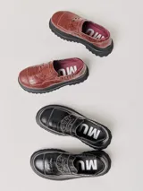 Mocasines de plataforma alta con diseño de estilo rebelde. Presentan un estampado de cuadros en tonos violeta y amarillo, confeccionados en lona con detalles en cuero. Cuentan con una suela robusta y elásticos laterales ocultos para facilitar el calce.