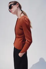 Chaqueta de punto color óxido, con cuello redondo, manga larga abullonada y cierre frontal con botones.