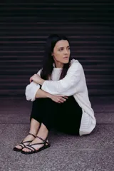 Sandalias planas de cuero negro con múltiples tiras finas adornadas con tachas doradas. Cuentan con cierre de hebilla en el tobillo.