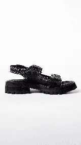 Sandalias de mujer con plataforma gruesa y dentada de color negro. La capellada presenta un estampado de piel de serpiente en tonos beige y marrón, con dos tiras ajustables con hebillas de cuero marrón.
