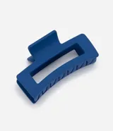 Pinza para el pelo color azul, de diseño rectangular y acabado mate, con diseño ahuecado en el centro y mecanismo de resorte metálico.