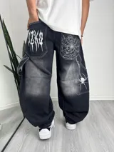 Pantalón de jean estilo baggy con corte carpintero, color negro con efecto lavado. Presenta bolsillos traseros amplios con bordados en hilo blanco: uno con tipografía gótica y otro con diseño de telaraña y araña colgante.