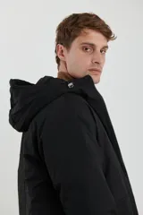 Campera impermeable negra con capucha, cierres a tono y cursores negros metalizados, bolsillos frontales con tapa, elásticos regulables en el ruedo e interior térmico con detalles confeccionados con láser.