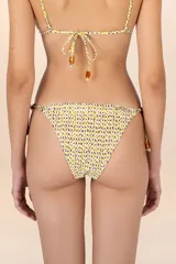 Calzón de bikini con estampado de manchas amarillas y violetas, con tiritas laterales ajustables adornadas con cuentas marrones.