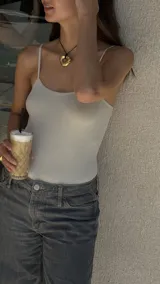 Collar con dije de forma irregular en tonos dorados y plateados, suspendido de un cordón doble de algodón negro.