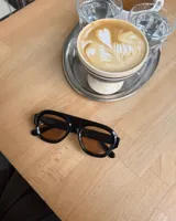 Lentes de sol con armazón de acetato negro y cristales tonalizados en color ámbar, con diseño de puente recto y estilo moderno.