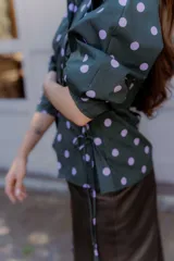 Camisa verde con lunares violetas, cuello clásico, mangas abullonadas y lazos laterales para ajustar.