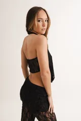 Top negro de encaje con cuello halter y abertura frontal.