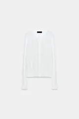 Chaqueta de punto blanco con diseño pointelle, cuello redondo, manga larga y cierre frontal con botones.