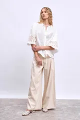 Blusa blanca de lino con cuello mao, mangas 3/4 abullonadas con apliques bordados en forma de hojas y cierre frontal con botones.