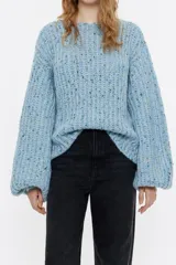 Jersey de punto celeste con hilo multicolor entrelazado. Modelo de corte recto, escote barco, manga maxilarga con volumen y costuras al revés.