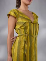 Vestido largo de lino y algodón con diseño de rayas verticales en tonos mostaza y verde. Presenta escote en V, cuello solapa ancho, mangas cortas con diseño capa, corte recto y lazo ajustable en la cintura.