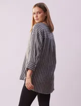 Blusa de poliéster con estampado de rayas verticales, cuello en V con botones, mangas tres cuartos y tajos laterales.