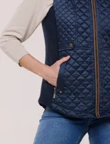 Chaleco acolchado de diseño entallado color beige, con matelaseado en patrón de rombos en frente y espalda, cuello alto estructurado y cierre frontal completo con cremallera metálica y ribete a contraste.
