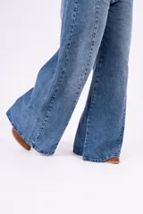 Jean de corte wide leg con costura central vertical en ambas piernas. Presenta un tono denim clásico, tiro medio y cierre frontal con botones.
