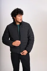 Campera acolchada negra con cierre frontal, cuello alto y diseño de costuras horizontales. Presenta un ajuste entallado y tejido exterior resistente al agua.