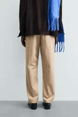 Pantalón chino de corte regular fit, confeccionado en tejido de algodón con elasticidad. Presenta bolsillos frontales, bolsillos traseros de vivo y cierre frontal con cremallera y botón.