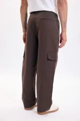 Pantalón cargo baggy color marrón, de corte holgado y pierna recta. Cuenta con bolsillos laterales tipo cargo en las piernas y bolsillos frontales de gran tamaño.