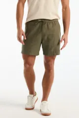 Short de lino color verde militar, de corte recto, con cintura elástica ajustable mediante cordón y bolsillos laterales.