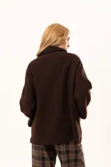 Tapado tipo poncho de silueta oversize, color marrón, confeccionado en paño. Presenta cuello alto con cierre frontal de cremallera niquelada, mangas anchas y bolsillos laterales.