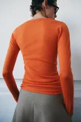 Jersey de punto fino color naranja, con cuello redondo y manga larga.