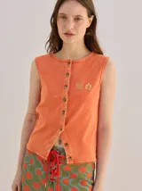 Musculosa de tejido de punto con efecto acid wash color naranja, corte recto, cierre frontal con botones y detalle de bordado en el pecho.