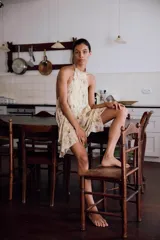 Top halter de tejido ligero con estampado floral en tonos tierra sobre fondo beige. Presenta diseño sin mangas, espalda descubierta y cierre con lazadas en el cuello y la espalda, con un bajo asimétrico.