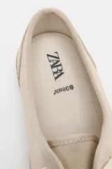 Zapatillas tipo deportiva confeccionadas en serraje color beige, con diseño barefoot de puntera amplia, suela flexible efecto engomado y cierre mediante cordones al tono.