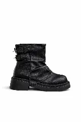 Botas negras de caña corta con efecto arrugado en el empeine, suela gruesa y dos hebillas decorativas en el lateral exterior.