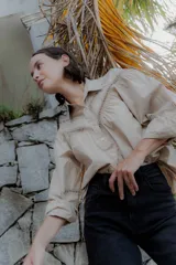 Camisa negra de algodón con detalles de encaje broderie en el pecho y mangas. Presenta cuello clásico, cierre frontal con botones y mangas largas abullonadas.