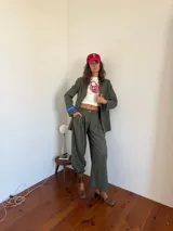 Blazer de sastrería con diseño oversize y hombreras pronunciadas. Presenta un estampado de rayas verticales finas, cierre frontal con botones nacarados y forrería a contratono. Incluye una etiqueta bordada decorativa en la manga.