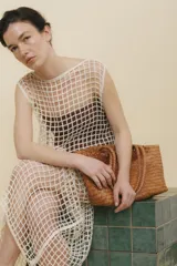 Bolso tipo tote de cuero vacuno, completamente trenzado a mano. El color es marrón oscuro, casi chocolate. Posee dos asas de hombro trenzadas.