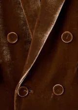 Blazer de terciopelo color marrón, con diseño de doble botonadura, solapas clásicas y bolsillos laterales con solapa. Presenta un corte estructurado y elegante.