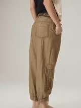 Pantalón de corte relajado color marrón, confeccionado en mezcla de algodón y lino. Presenta cintura con pasacintos, bolsillos laterales y diseño de botamanga ajustable con cordones y elástico.