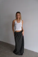 Pollera larga de fibrana color bordó con estampado de lunares blancos, tiro alto y corte amplio.