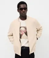 Campera tipo bomber masculina de color beige, con cuello, puños y ruedo acanalados. Presenta cierre frontal por cremallera, bolsillos laterales y acabado con tecnología repelente al agua.