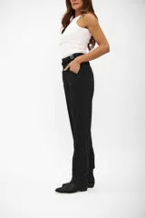 Pantalón negro de vestir, tiro alto, con pinzas frontales y corte recto y holgado que termina por encima del tobillo. Posee trabillas para cinturón y bolsillos laterales.