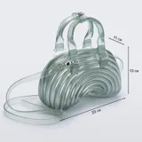 Cartera Melissa modelo Quantum Dome, hecha de PVC translúcido con efecto glitter plateado y diseño curvo de líneas concéntricas en relieve. Cuenta con doble asa de mano y correa larga ajustable y desmontable.
