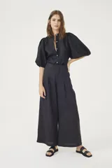 Pantalón culotte negro de lino orgánico, con cintura alta, diseño plisado y bolsillos laterales.